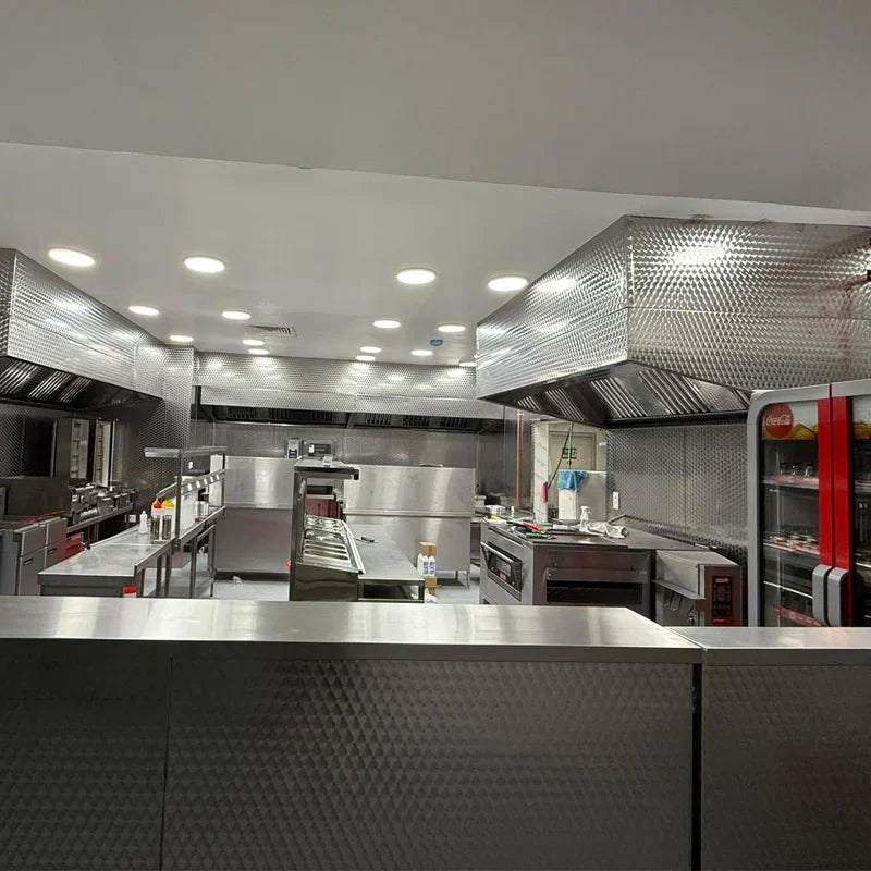 Commercial kitchen with stainless steel equipment, ventilation hoods, and prep stations