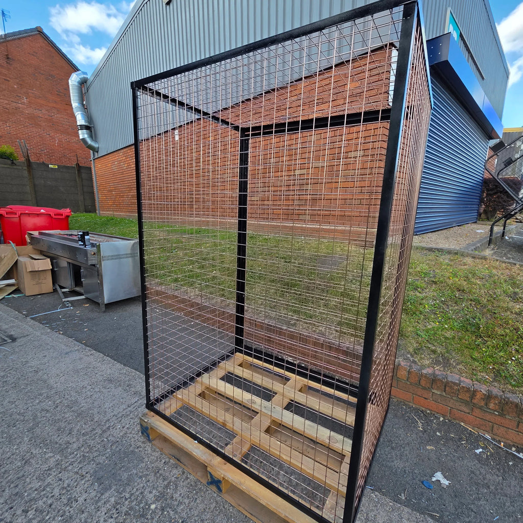Gas Bottle Cilander Cage Large metal mesh cage with black frame on wooden pallet, outdoor industrial setting