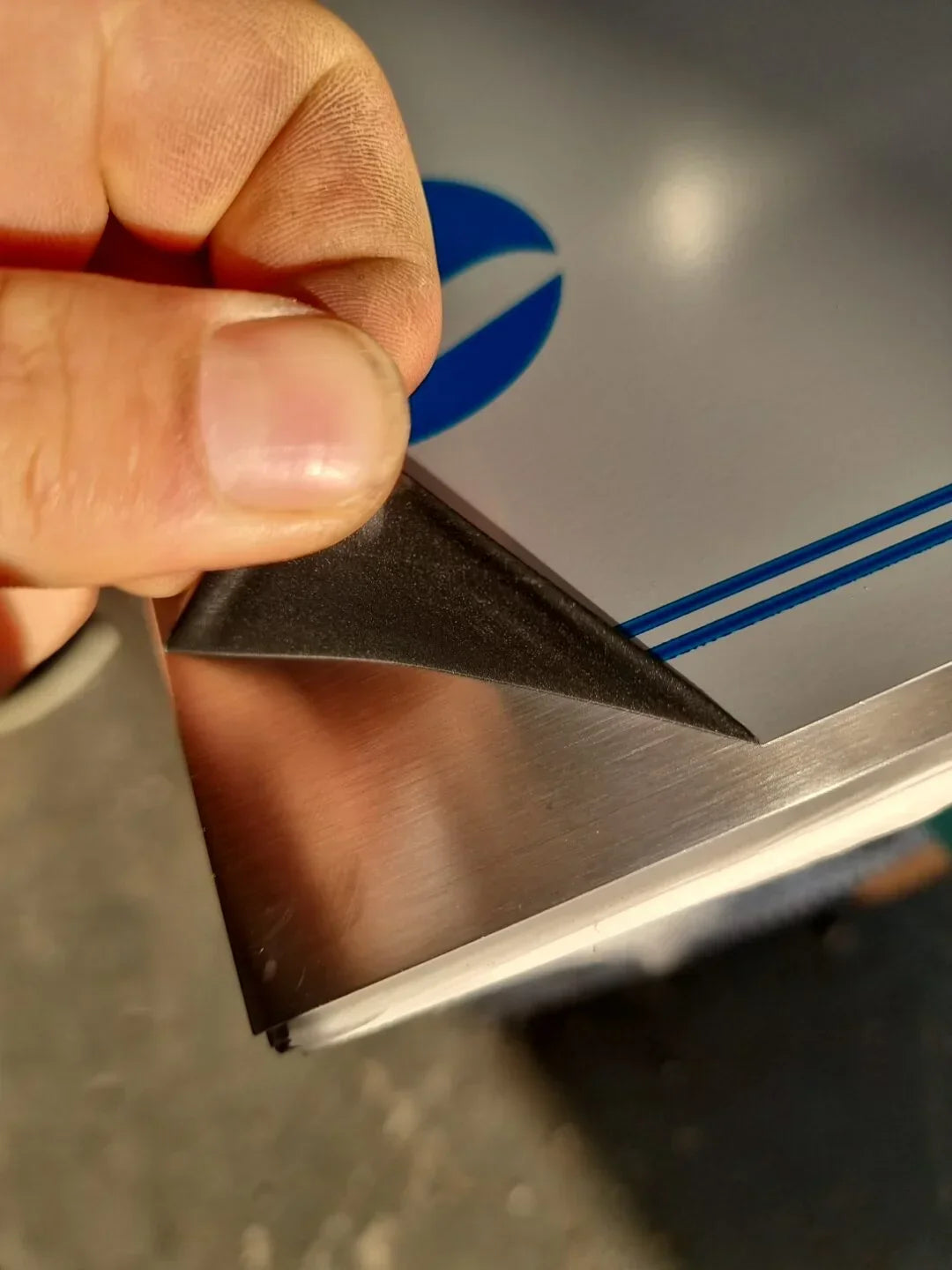 Hand applying black corner protector to metal frame edge