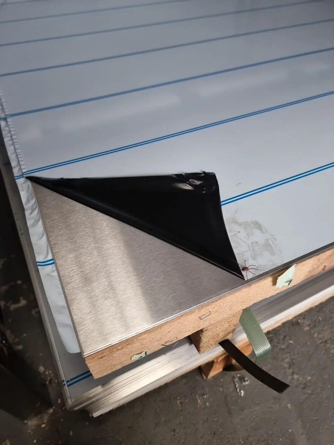 Stainless steel sheet with black protective film on lined surface, industrial material stack