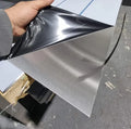 Brushed aluminum sheet with protective film being peeled, showcasing metallic finish and industrial use